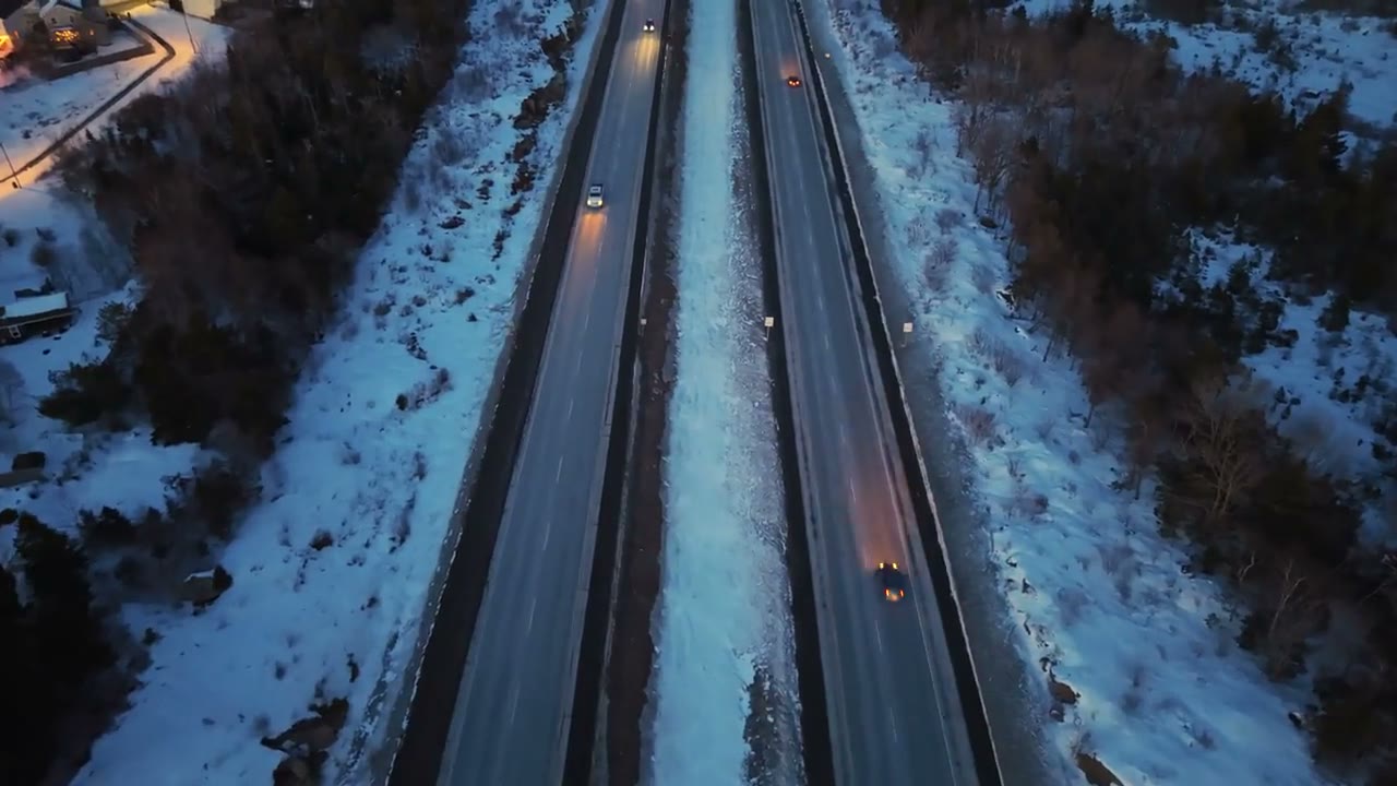 Headlights strung along a mountain highway at blue hour